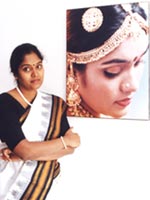 Archana poses next to her portrait at home